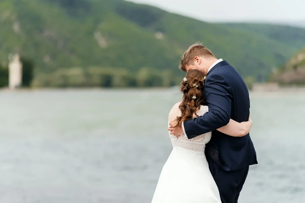 Braut und Bräutigam umarmen sich am Rheinufer