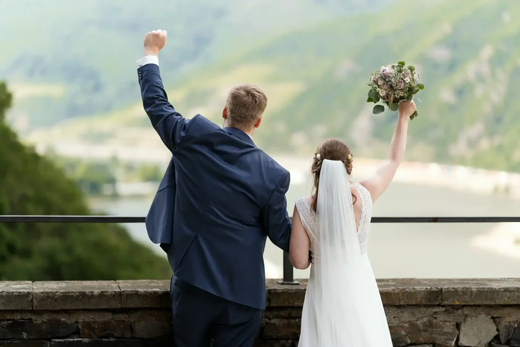 Brautpaar halten Hände in die Luft auf der Burg Rheinsteiin