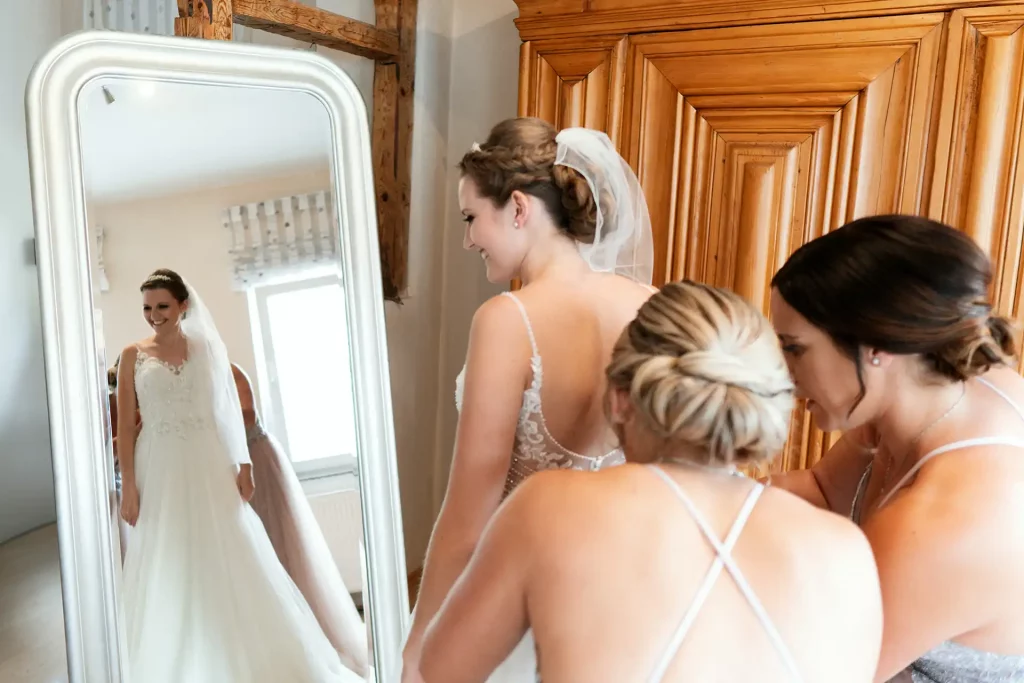 Trauzeuginnen helfen beim anziehen des Brautkleids
