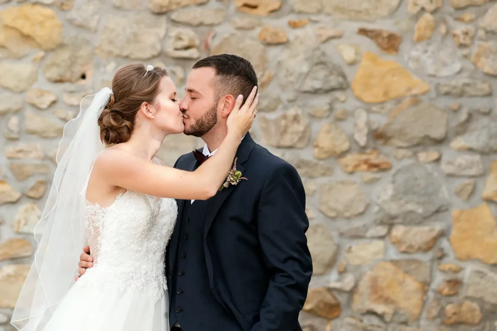Braut küsst Bräutigam leidenschaftlich und hält dabei den Kopf des Bräutigams fest