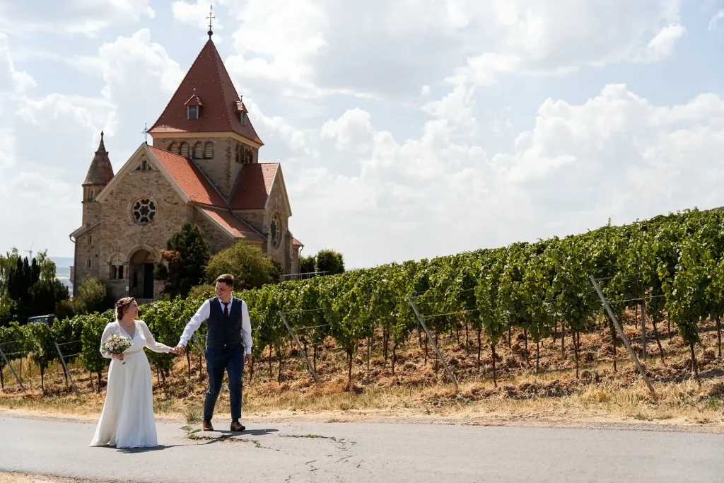 Brautpaar läuft Hand in Hand in den Weinbergen der Kreuzkapelle Gau-Bickelheim